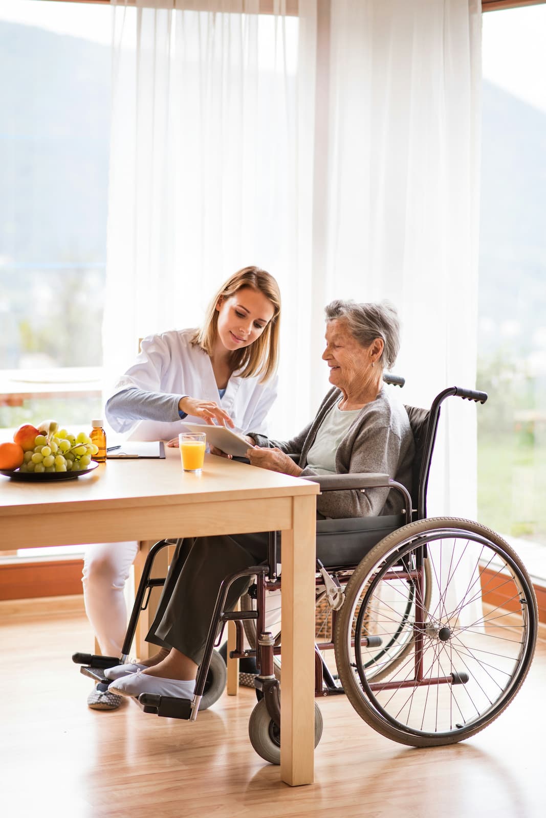 A carer settling an older woman back at home at her kitchen table